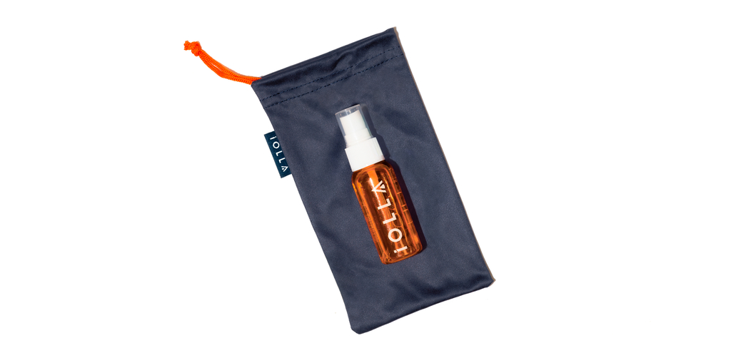 Navy cloth bag with orange drawstring, orange 30ml lens cleaner positioned on top of bag