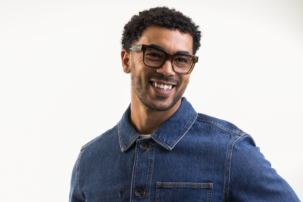 Male model wearing Brodie glasses in husk crystal smiling front profile