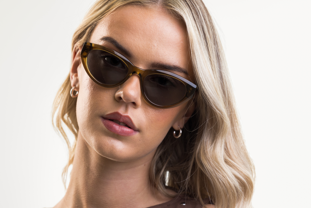 Female model wearing Jura sunglasses in husk crystal with green lenses front profile