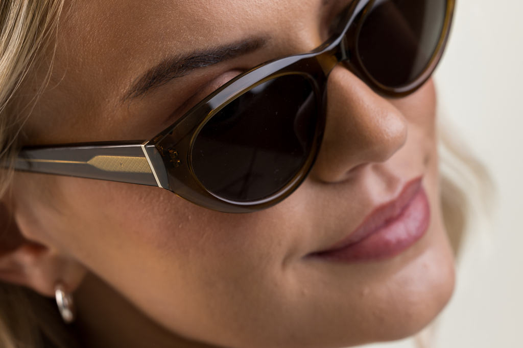 Female model wearing Jura sunglasses in husk crystal with green lenses top angle profile
