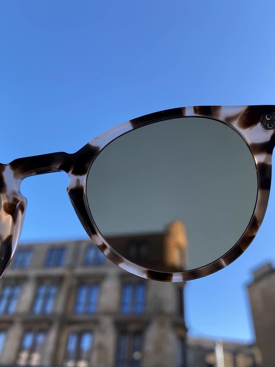 View of a building and blue sky through lens of sunglasses
