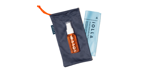 Navy cloth bag with orange drawstring, orange IOLLA lens cleaner on top with a folded blue cleaning cloth folded beside