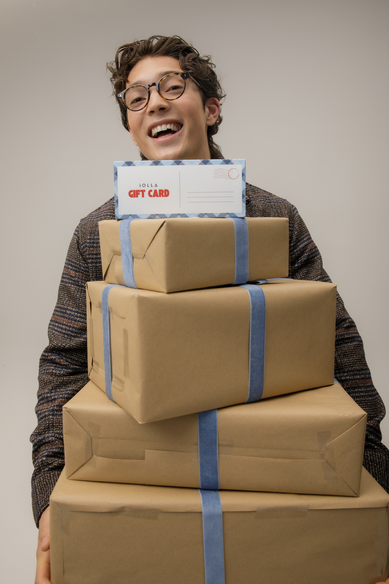 Laughing man in IOLLA glasses holding Christmas presents with an IOLLA gift card on top