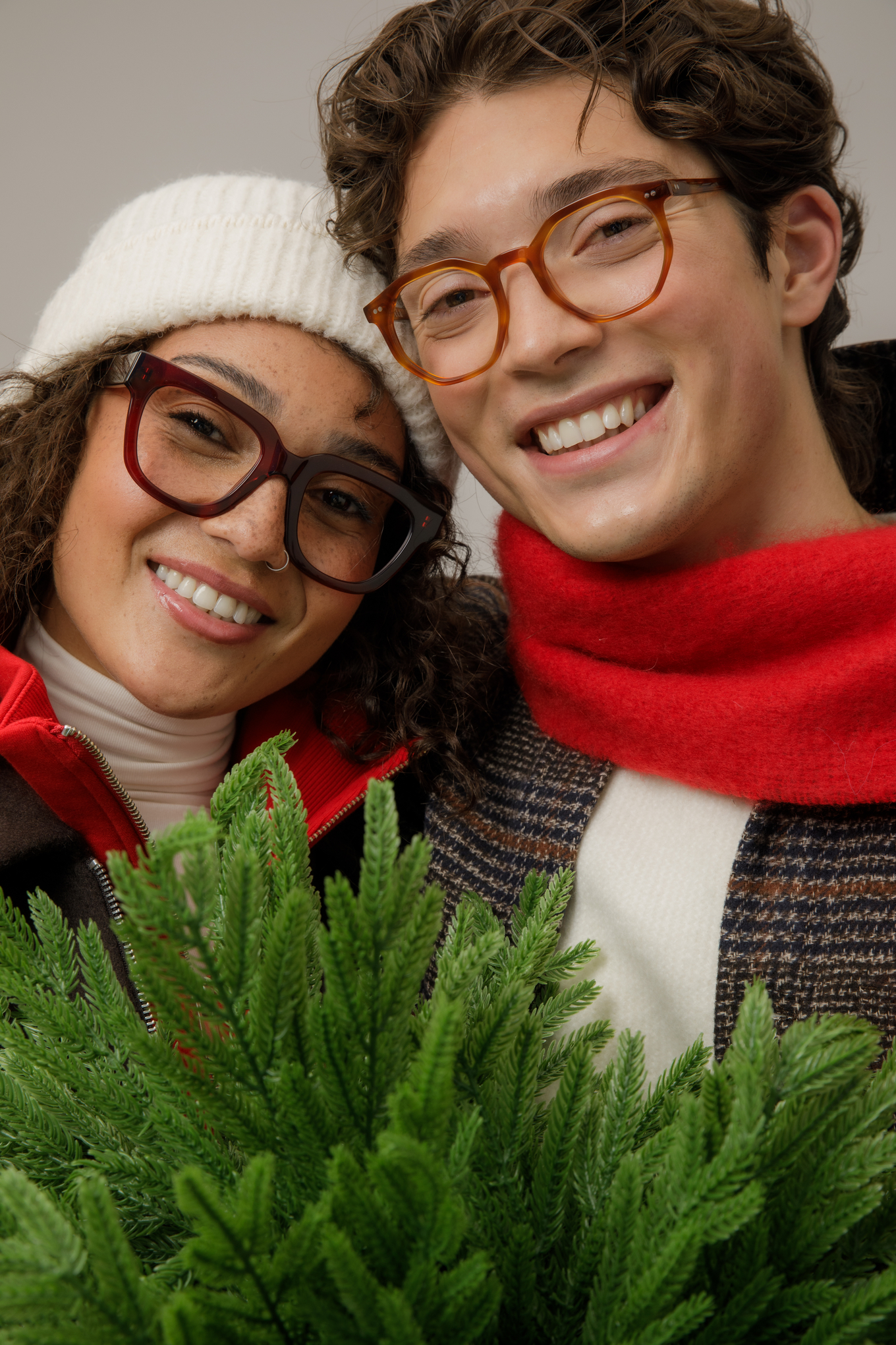 Smiling couple wearing IOLLA prescription glasses beside a Christmas tree