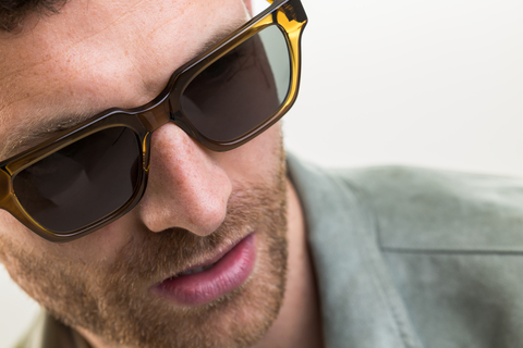 Male model wearing Macrae sunglasses with green lenses top angle profile